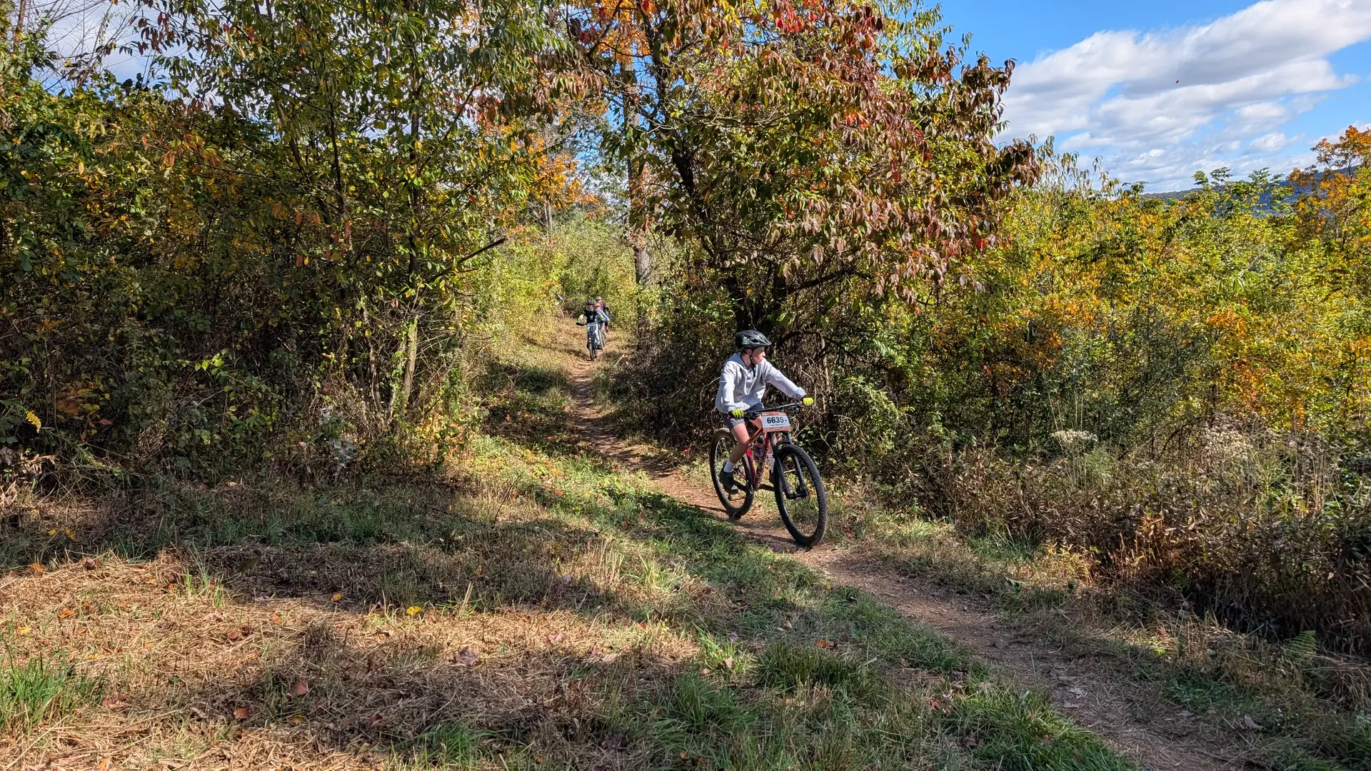 Teammates ride a winding trail through autumn trees at Raystown.